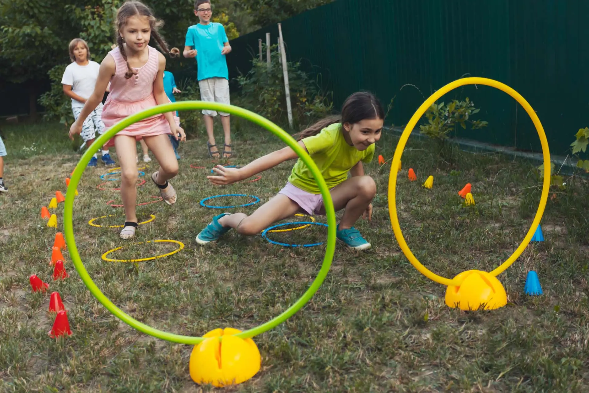 Two girls are competing in a sports game in the backyard. Behind them are other children waiting their turn