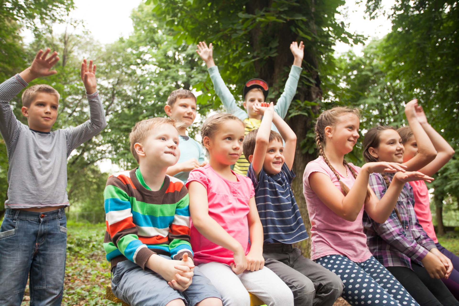 Group of positive children playing in the park sitting on the bench